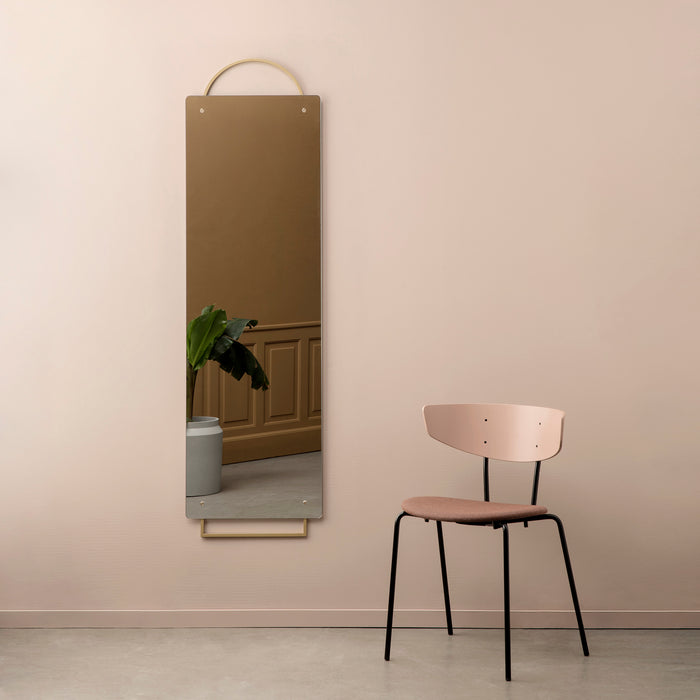 Een hoge, smalle Ferm Living Adorn Mirror spiegel wordt vergezeld door een Herman Chair stoel met gebogen rugleuning