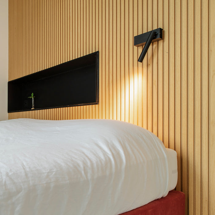 Davide Groppi spotverlichting, bevestigd aan een verticaal gegraveerd houten wandpaneel in de slaapkamer
