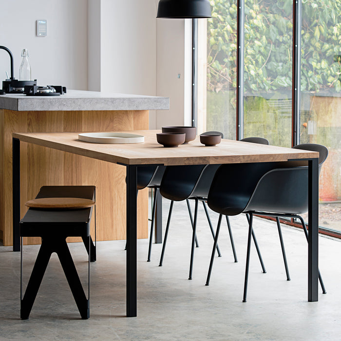 Rechte maatwerk tafel die aansluit op een houten kookeiland met betonlook werkblad