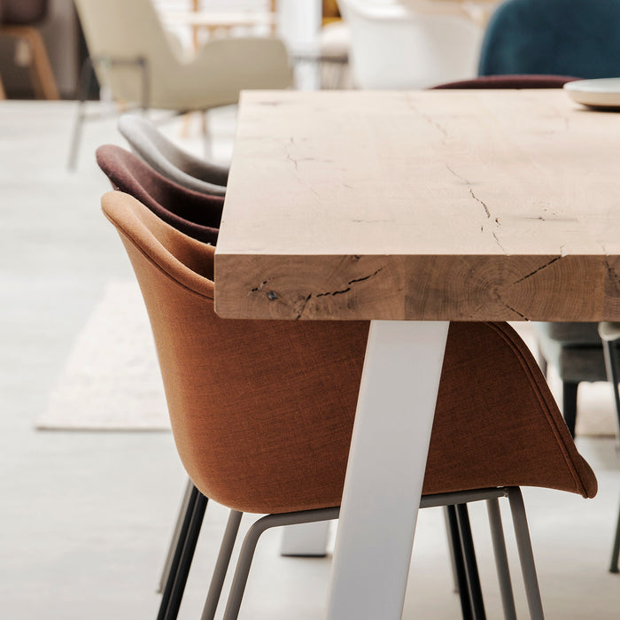 gestoffeerde Muuto Fiber stoelen aan houten maatwerk tafel met eiken blad en wit stalen onderstel