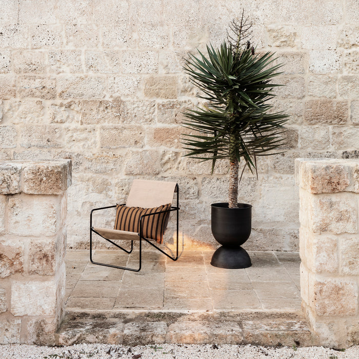 Buiten loungen in stijl met de Desert Lounge Chair tuinstoel en Hourglass plantenpot van Ferm Living