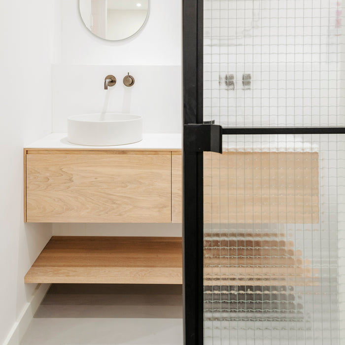 Stalen schuifdeur met draadglas in een badkamer met massief houten badmeubel
