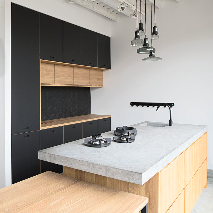 Zwarte keuken met houten kookeiland voorzien van een betonlook composiet werkblad inclusief gootsteen