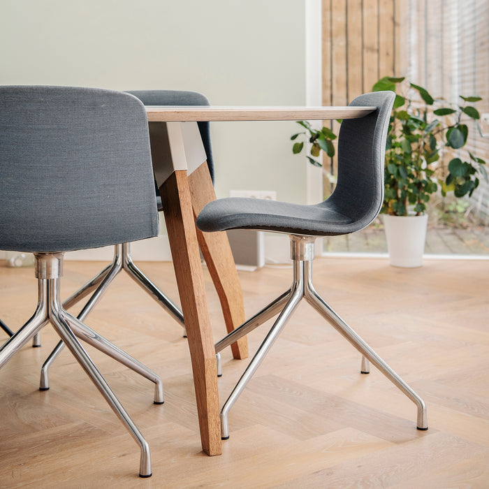 Grijsblauw gestoffeerde Hay AAC stoelen met draaibaar chroom onderstel aan ovale maatwerk designtafel Lino